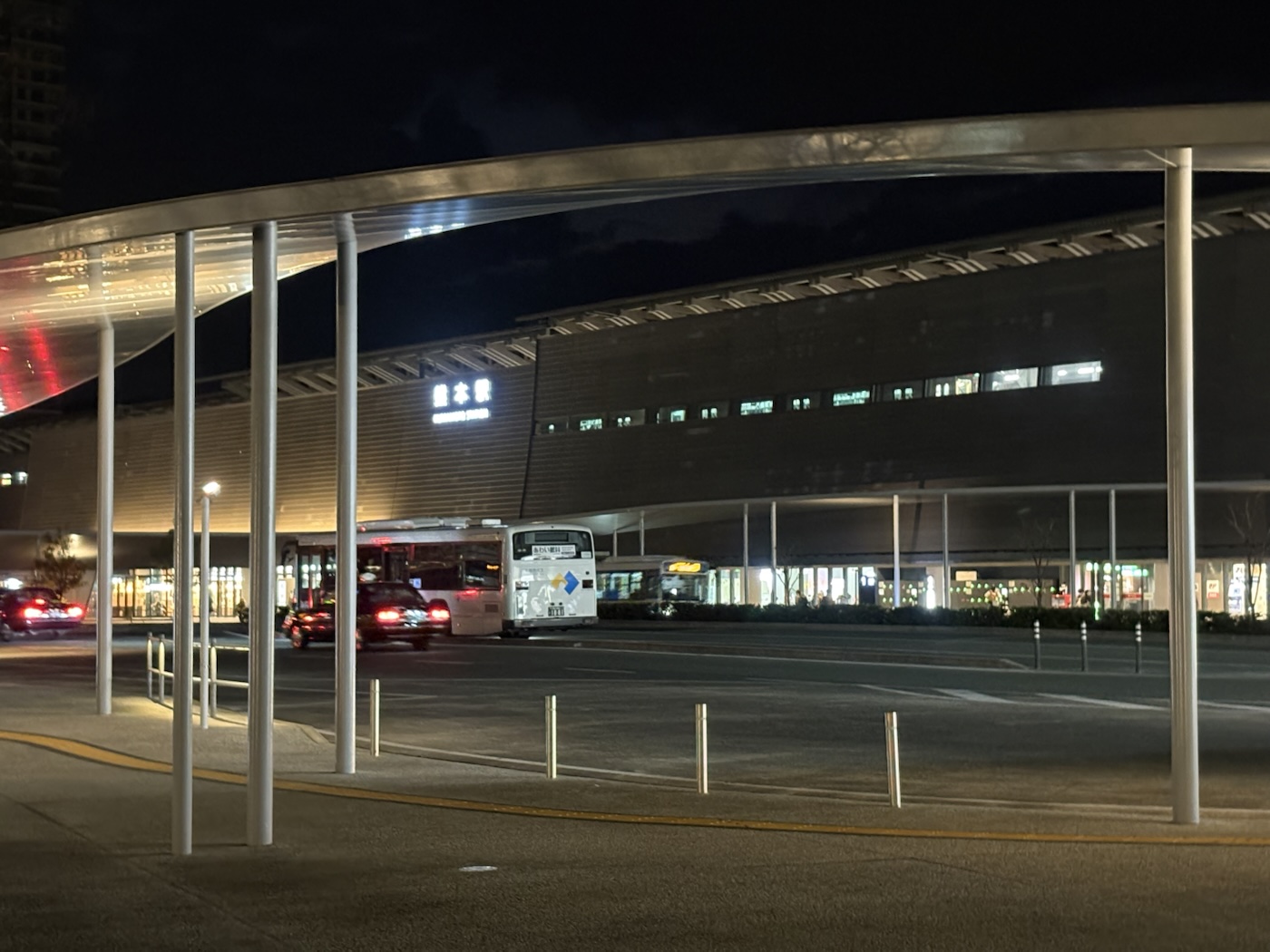 明かりのともった熊本駅と駅前のバス